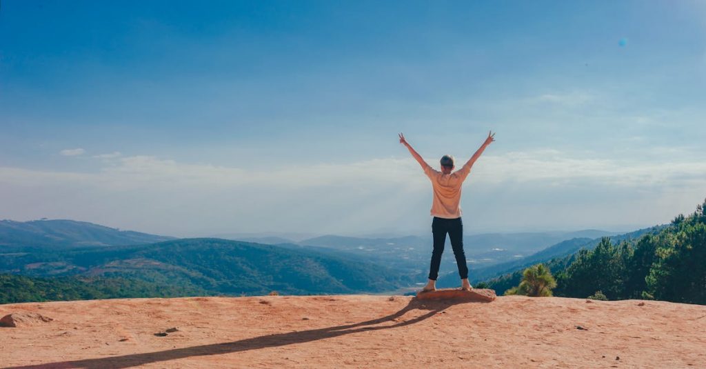 pexels-photo-1134188-1134188-1 A man raises his arms in triumph on a rocky mountain summit overlooking a vast landscape